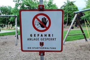 Ein gesperrter Spielplatz, das Schild warnt Eltern und Kinder vor Gefahr