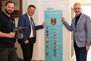 Bürgermeister Christian Scheider und Städtepartnerschaftsreferent MMag. Dr. Alexander Kastner beim Anbringen der Tafel im Eingangsbereich des Klagenfurter Rathauses. Foto: StadtKommunikation/Zechner