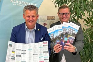 Bürgermeister Christian Scheider und Wirtschafts- und Tourismusreferent Stadtrat Julian Geier mit druckfrischen Exemplaren des Folders „Sommer Events in Klagenfurt am Wörthersee“. Foto: StadtKommunikation