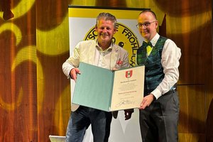 Bürgermeister Christian Scheider überreicht „Musikschule Fröhlich“-Leiter Adrian Holzer die „Dank und Anerkennung“-Urkunde. Foto: Büro Bürgermeister