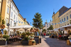 „Dirndl trifft Lederhose“ bringt Oktoberfeststimmung auf den Alten Platz. Foto: Mein Klagenfurt/KI-manipuliert