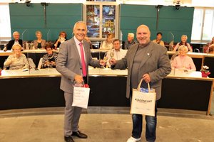 Vizebürgermeister Jürgen Pfeiler und der Dessauer Partnerschaftsvertreter Ralf Schüler tauschen einander Geschenke aus. Foto: StadtKommunikation / Rosenzopf