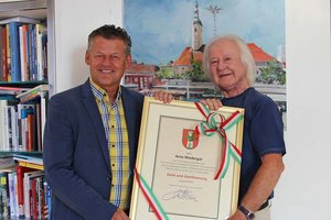 Bürgermeister Christian Scheider überreicht dem ehemaligen APA-Kärnten-Chef Arno Wiedergut die „Dank und Anerkennung“-Urkunde. Foto: StadtKommunikation / Wedenig