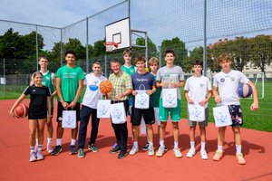 Bürgermeister Christian Scheider gemeinsam mit Safet Smajlović (links neben dem Bürgermeister) und den Basketballspielern vor Ort am Koschatplatz. Foto: StadtKommunikation / Hude